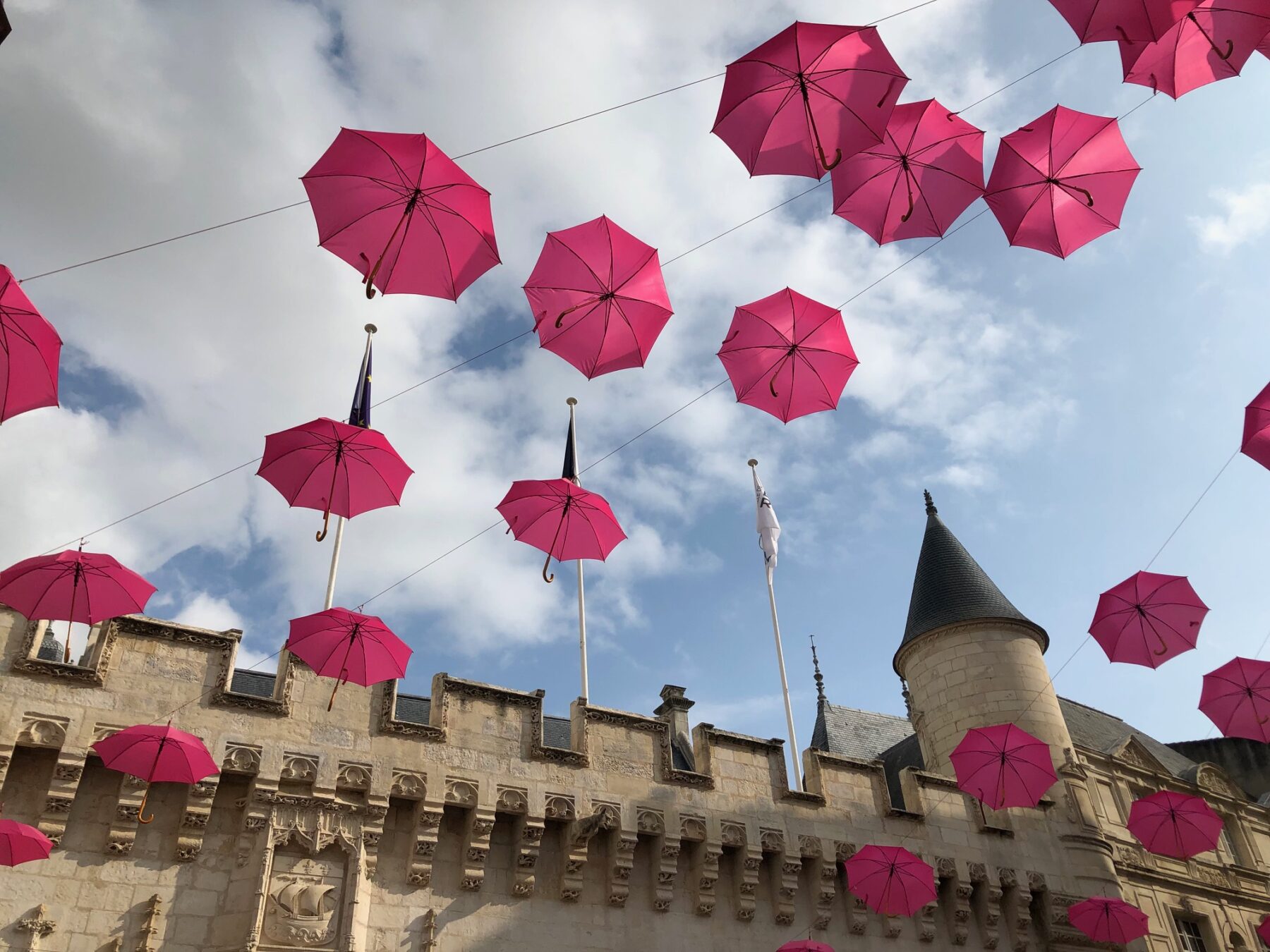 フランスの地方都市でピンクの傘が空に浮かんでいる画像